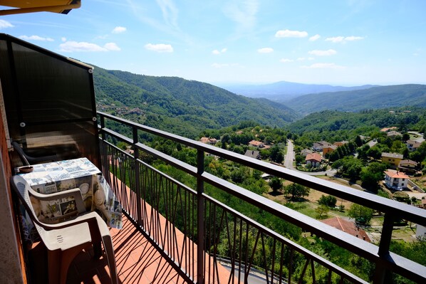 A balcony with a view of a valley and distant mountains.