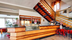 A bar area with a wooden counter, a staircase, and a seating area with red chairs. - Amelia Dream View (Marliana)