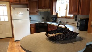A kitchen with wooden cabinets, a white refrigerator, a stove, a sink, and a microwave. - Rustic Log Cabin next to the Hoosier National Forest in the Ohio River Valley (Derby)