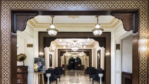 Un lobby majestuoso con piso de mármol, marcos de madera ornamentados y candelabros.