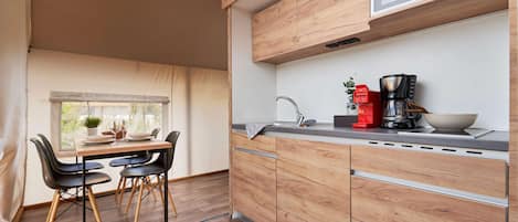A modern kitchen with wooden cabinets, a microwave, a coffee maker, and a dining area with a table and chairs.