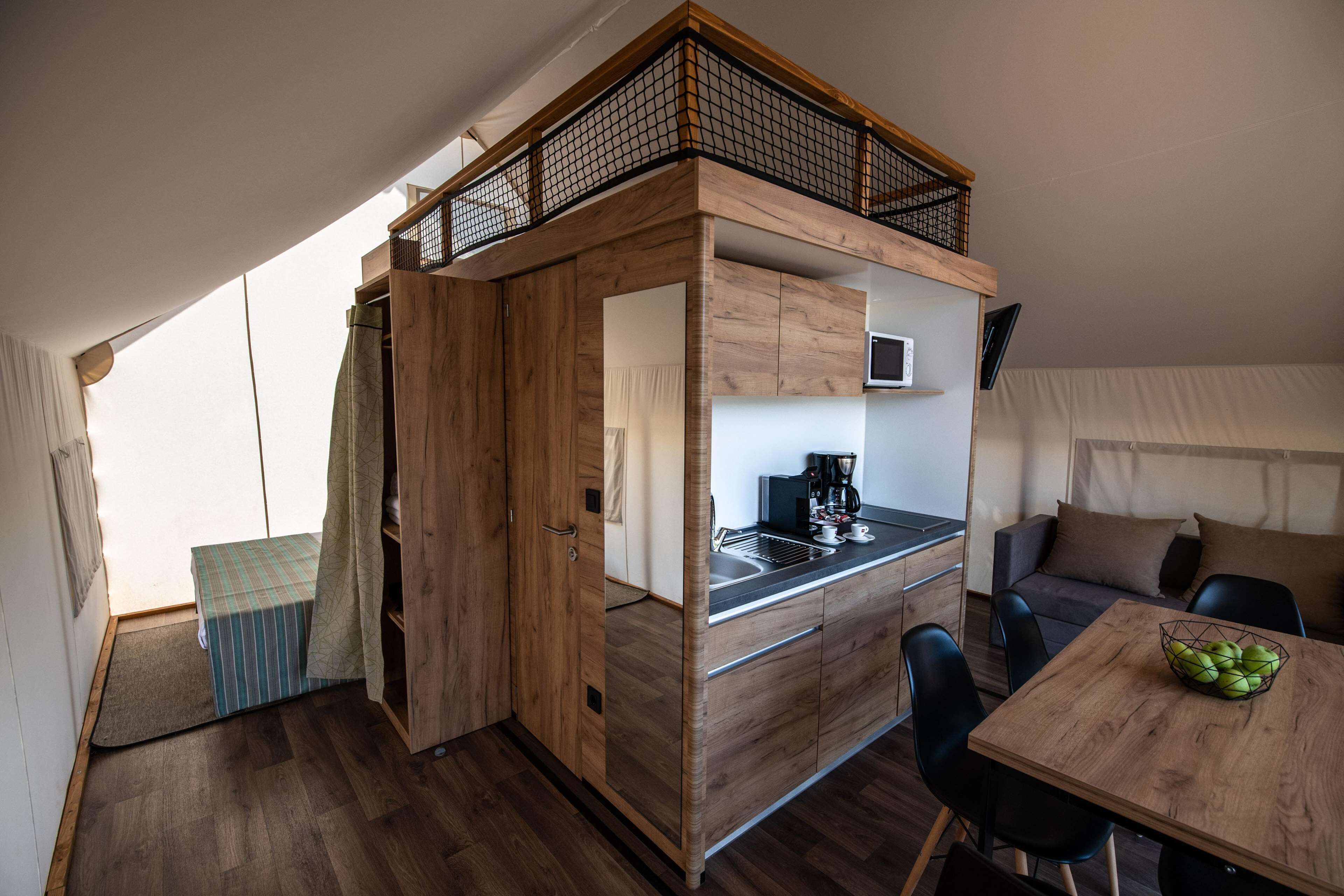 A compact, modern kitchenette with a wooden design, a dining area with a table and chairs, and a small seating area with a sofa.