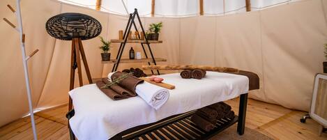 Una tienda acogedora y bien iluminada con cama, ventilador y estantes con artículos de aseo.