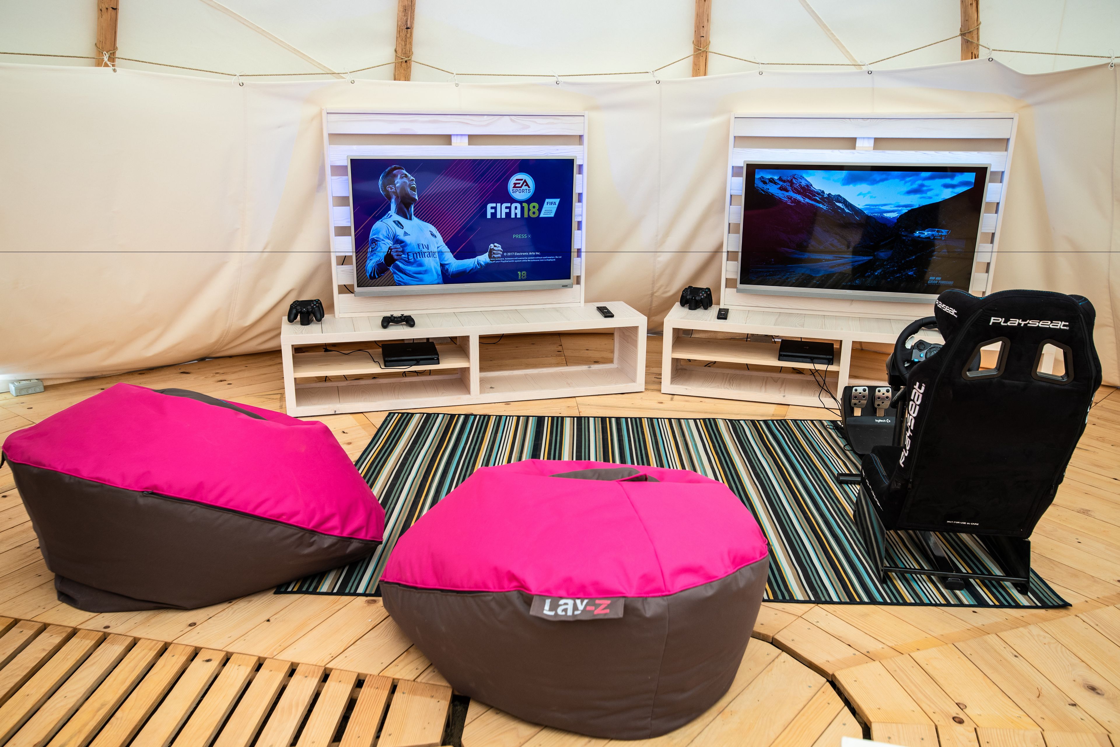 A gaming setup with two TVs, gaming chairs, bean bags, and a PlayStation 5 console.