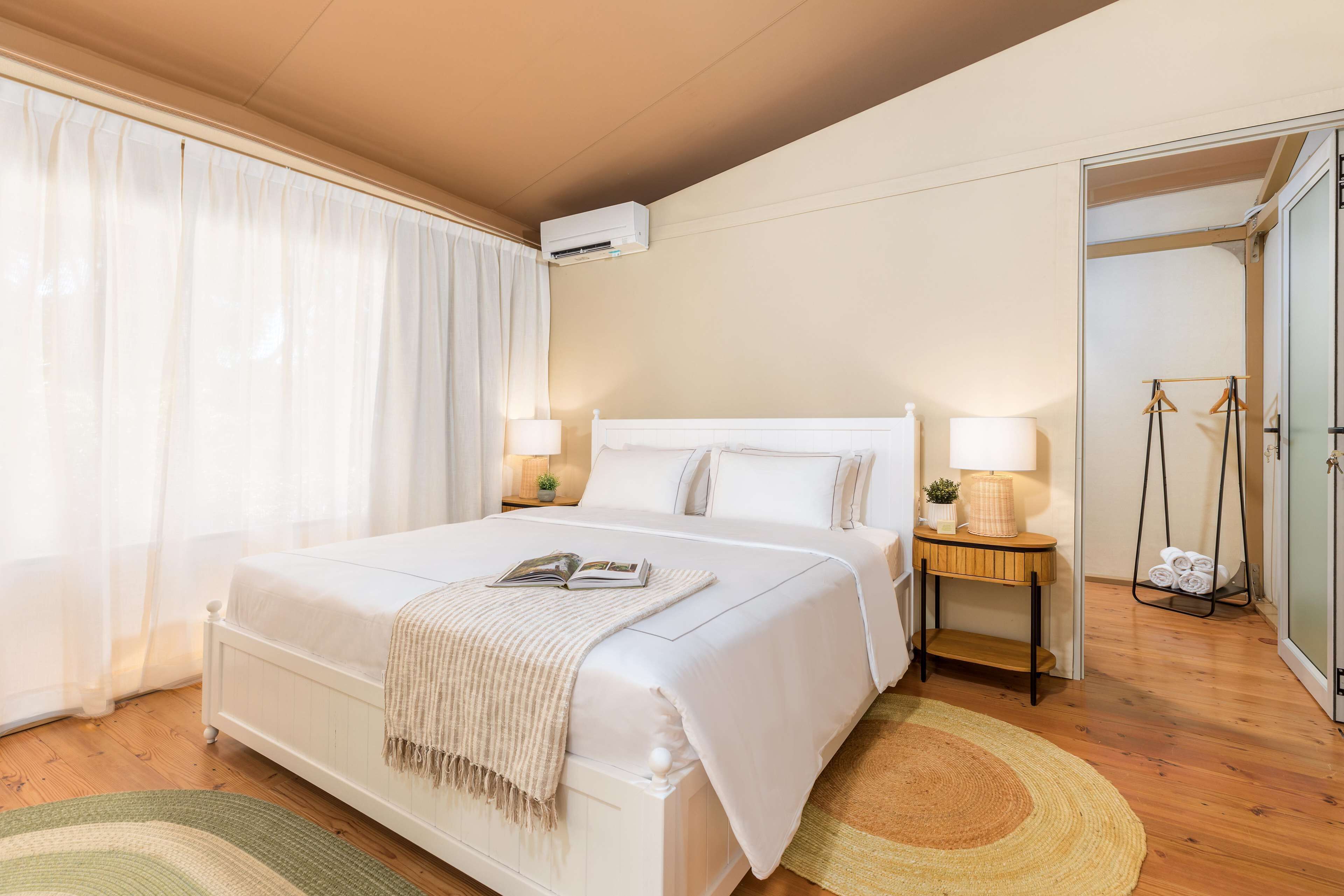 Une chambre d’hôtel avec un grand lit, une table de chevet avec une lampe et un porte-vêtements suspendu.
