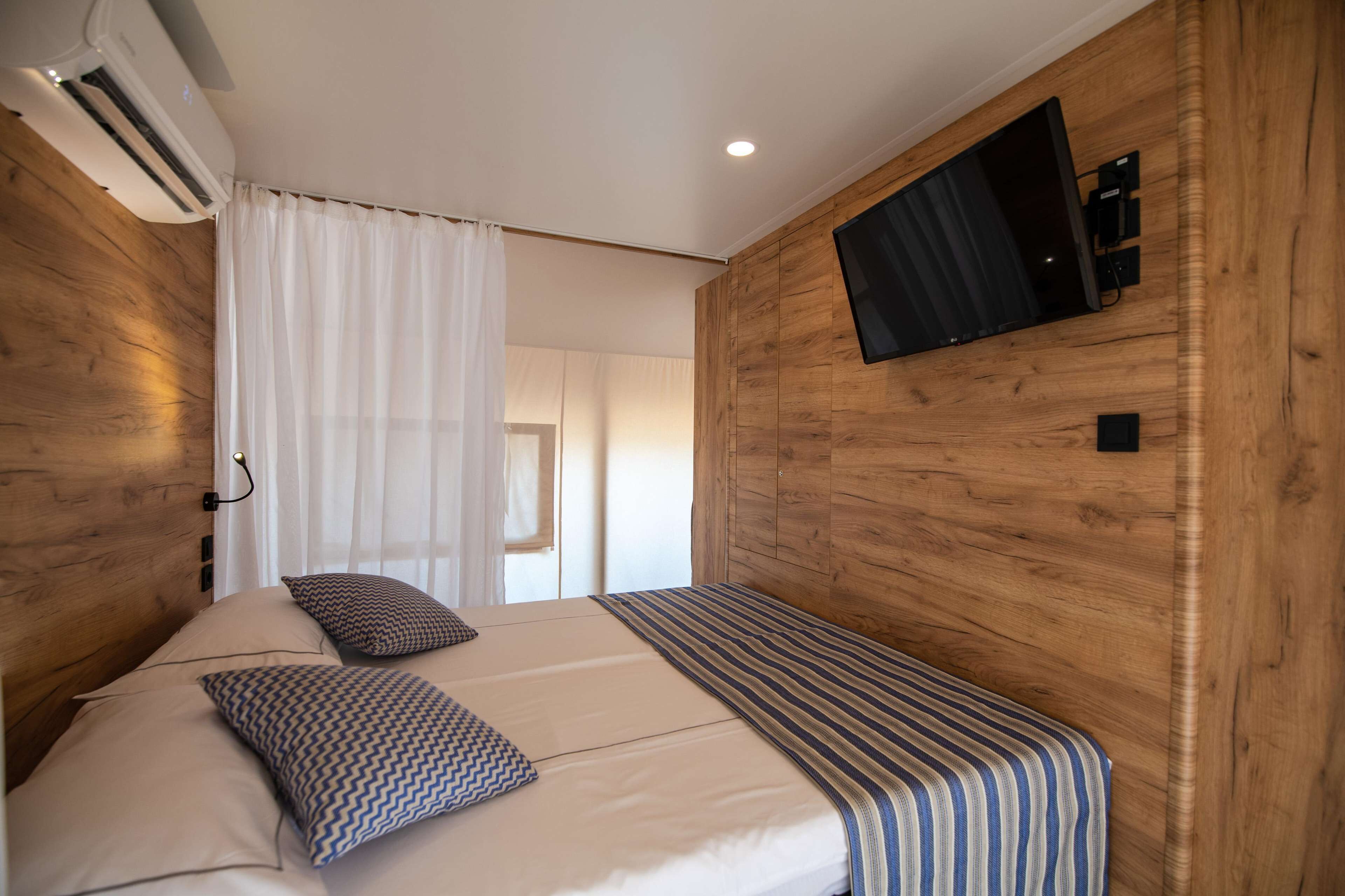 Une chambre à coucher avec un lit, un téléviseur fixé au mur et un appareil de climatisation.