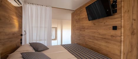 Une chambre à coucher avec un lit, un téléviseur fixé au mur et un appareil de climatisation.