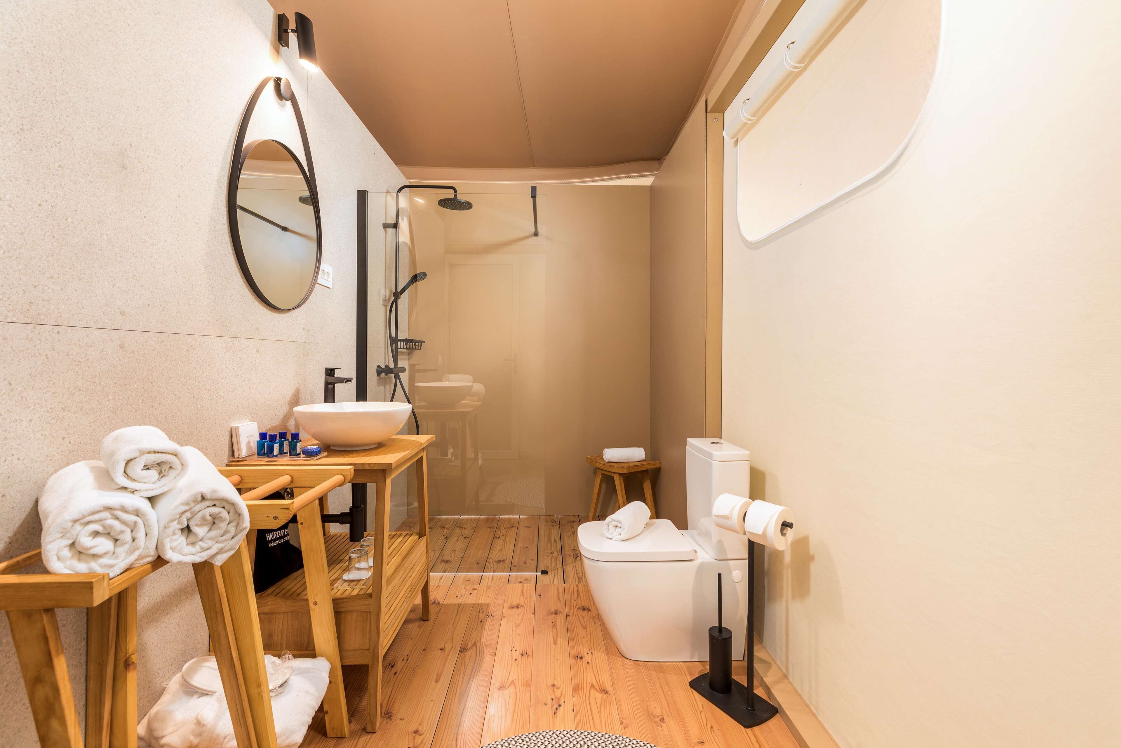 Un bagno compatto con un mobile bagno in legno, un lavabo, un water e uno spazio doccia.