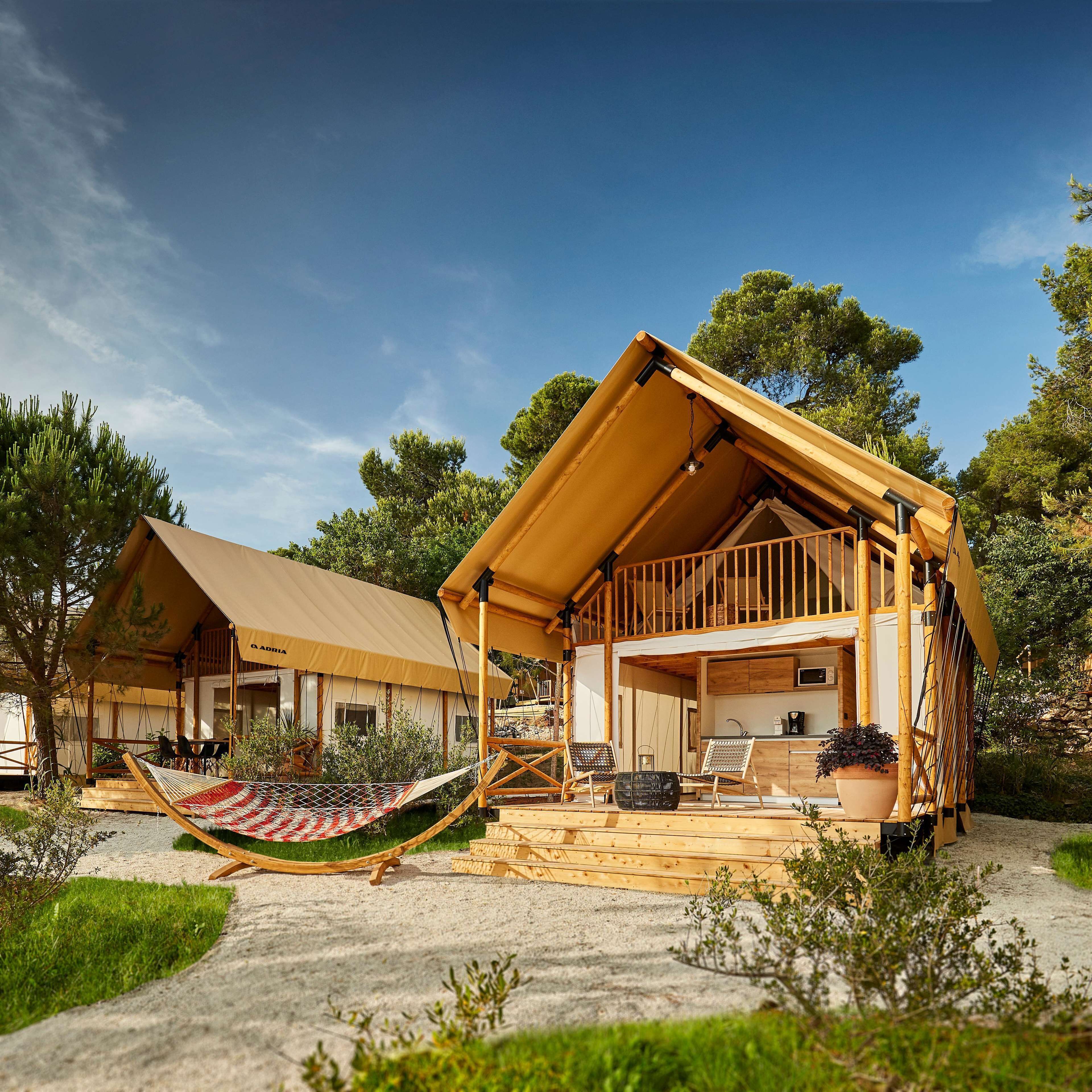 A wooden cabin with a balcony, a hammock, and a kitchen area.
