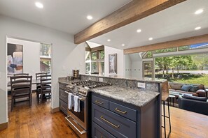 A modern kitchen with a large island, wooden beams, and a view of the outdoors. - 🏆 Breck Home | Hot Tub | 5 Kings | Sleeps 16 | Game Room | Free Town Shuttle (Breckenridge)