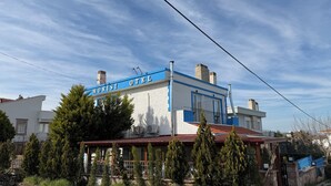 Un hotel con fachada azul y blanca, múltiples chimeneas y una unidad de aire acondicionado visible.