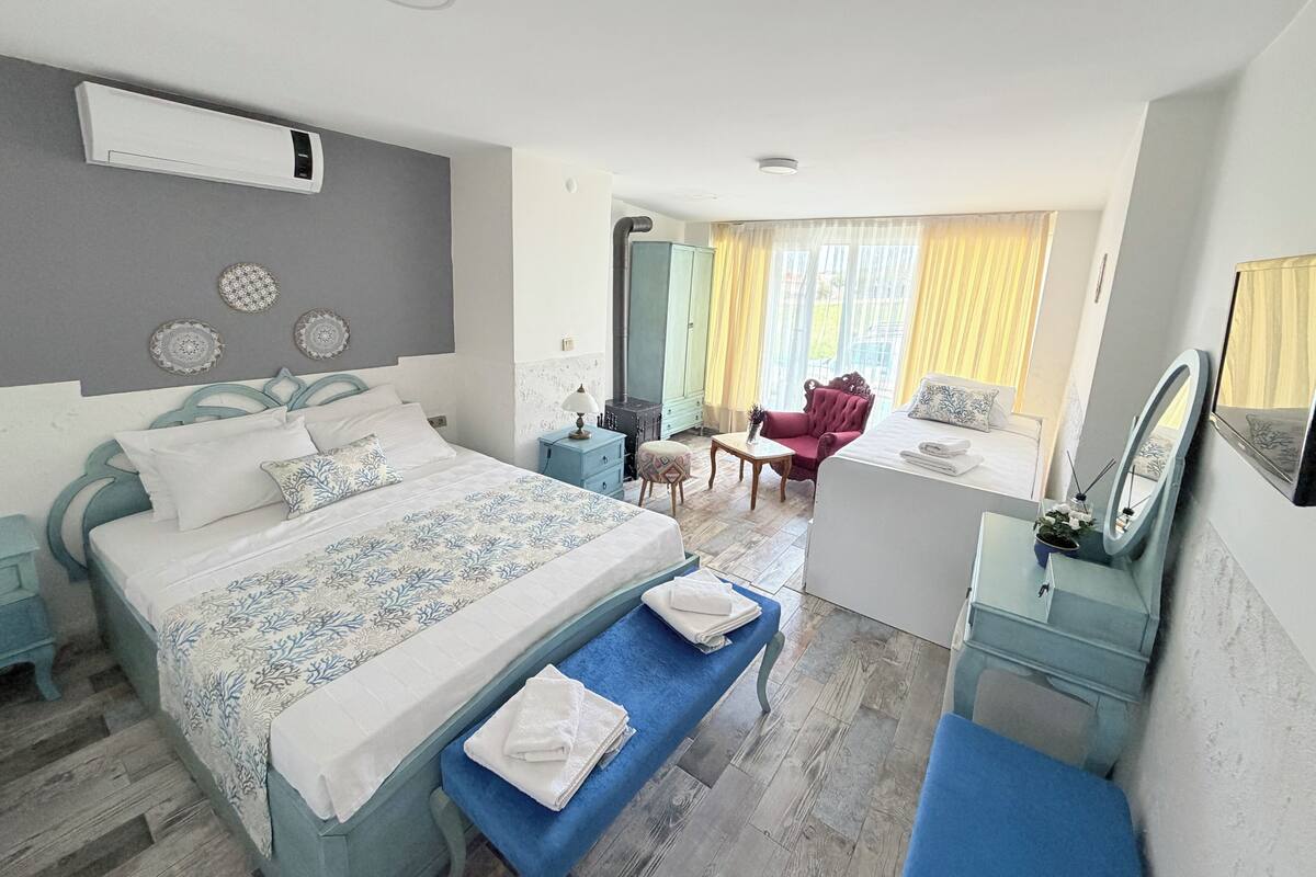 A well-lit bedroom with a large bed, bedside tables, a desk, and a chair.