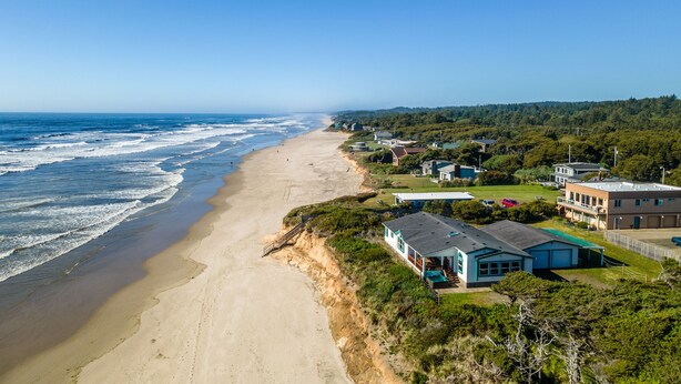 A coastal property with a beach view, a swimming pool, and a large house with a garage. - Ocean Front Home With Hot Tub On Miles Of Sandy Beach! (Yachats)
