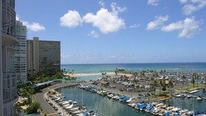 Un puerto deportivo con barcos amarrados, una playa y edificios altos al fondo.