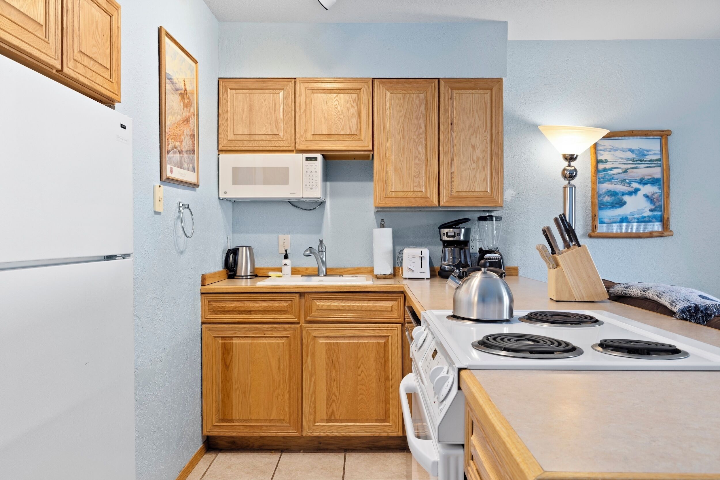 A kitchen with wooden cabinets, a microwave, a stove, and a sink.