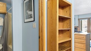 Ein Badezimmer mit Dusche, Toilette und einem Holzschrank mit Regalen.