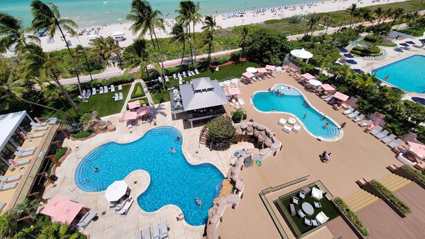 Ein Resort mit mehreren Schwimmbecken, Liegebereichen und einem Strand.