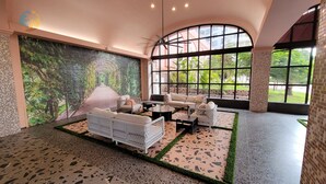Ein großzügiger Innenbereich mit einem hohen Bogenfenster, einem Deckenventilator und einer Sitzecke mit Sofas und einem Couchtisch.
