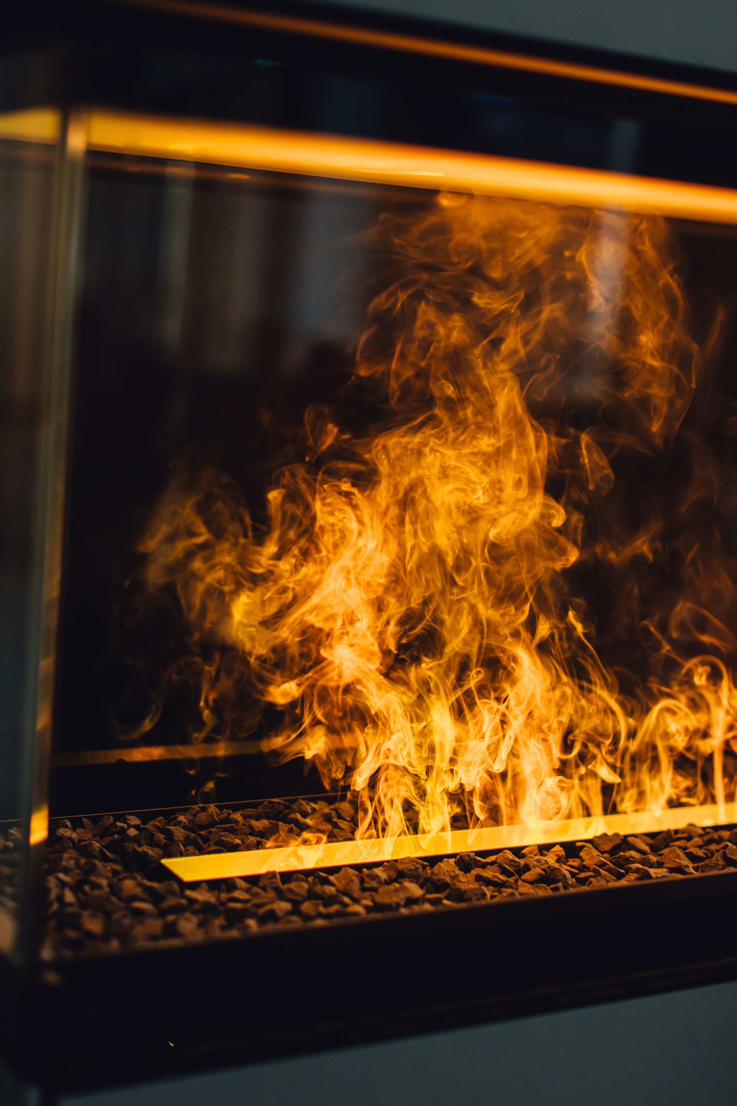 A close-up of a fire burning in a glass enclosure with a metal grate at the bottom.
