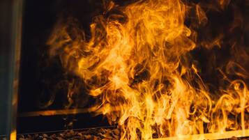 A close-up of a fire burning in a glass enclosure with a metal grate at the bottom.