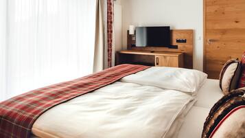Una habitación de hotel con una cama, un televisor sobre un mueble de madera, un escritorio y una puerta.
