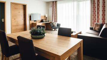 Un salon moderne avec une table à manger en bois, des chaises noires, un canapé et un téléviseur fixé au mur.