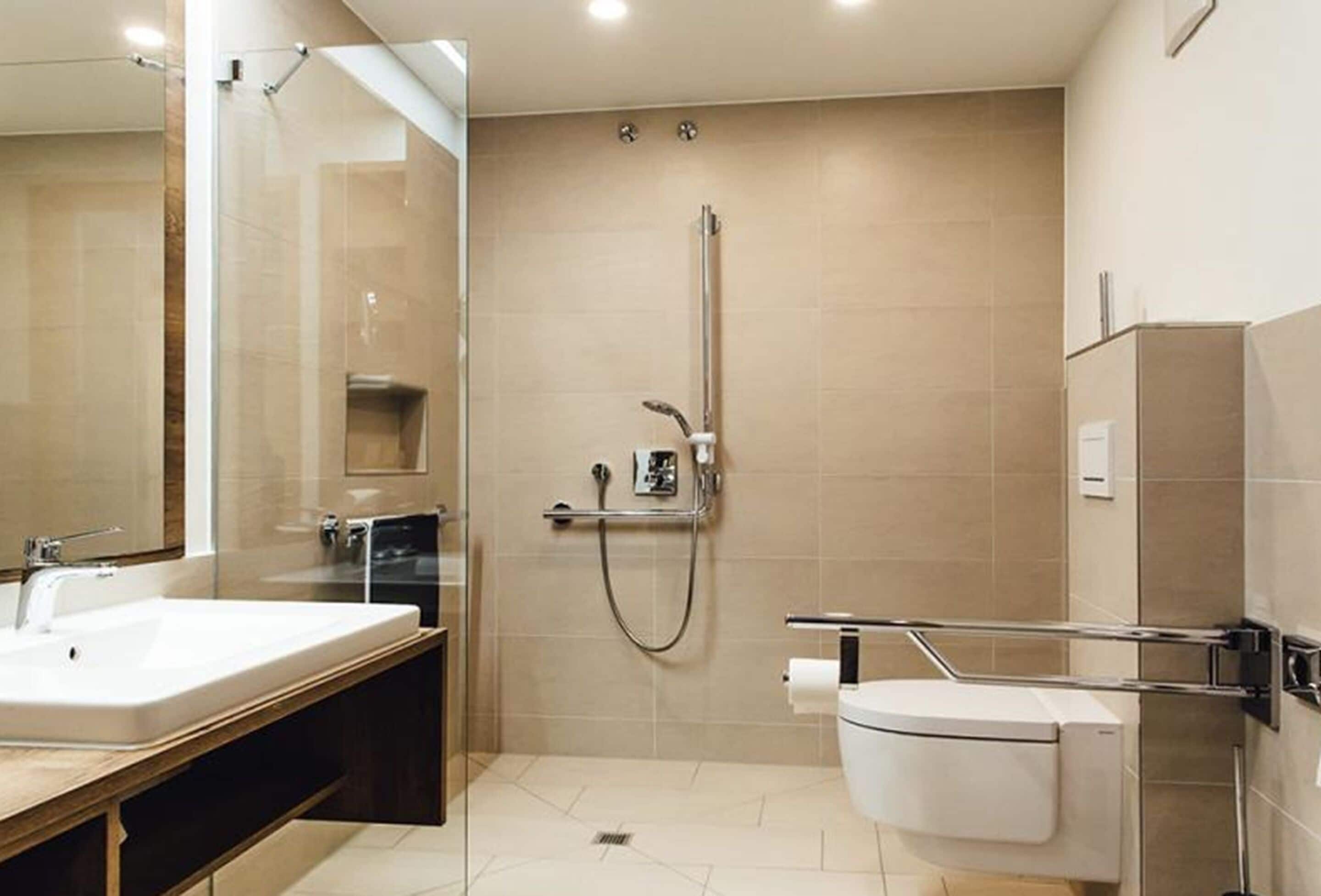 A modern bathroom with a large mirror, a sink, a toilet, and a shower.