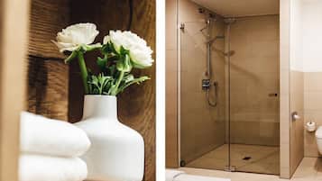 Ein Badezimmer mit einer Glaskabine zur Dusche, einer weißen Badewanne und einer weißen Vase mit Blumen.