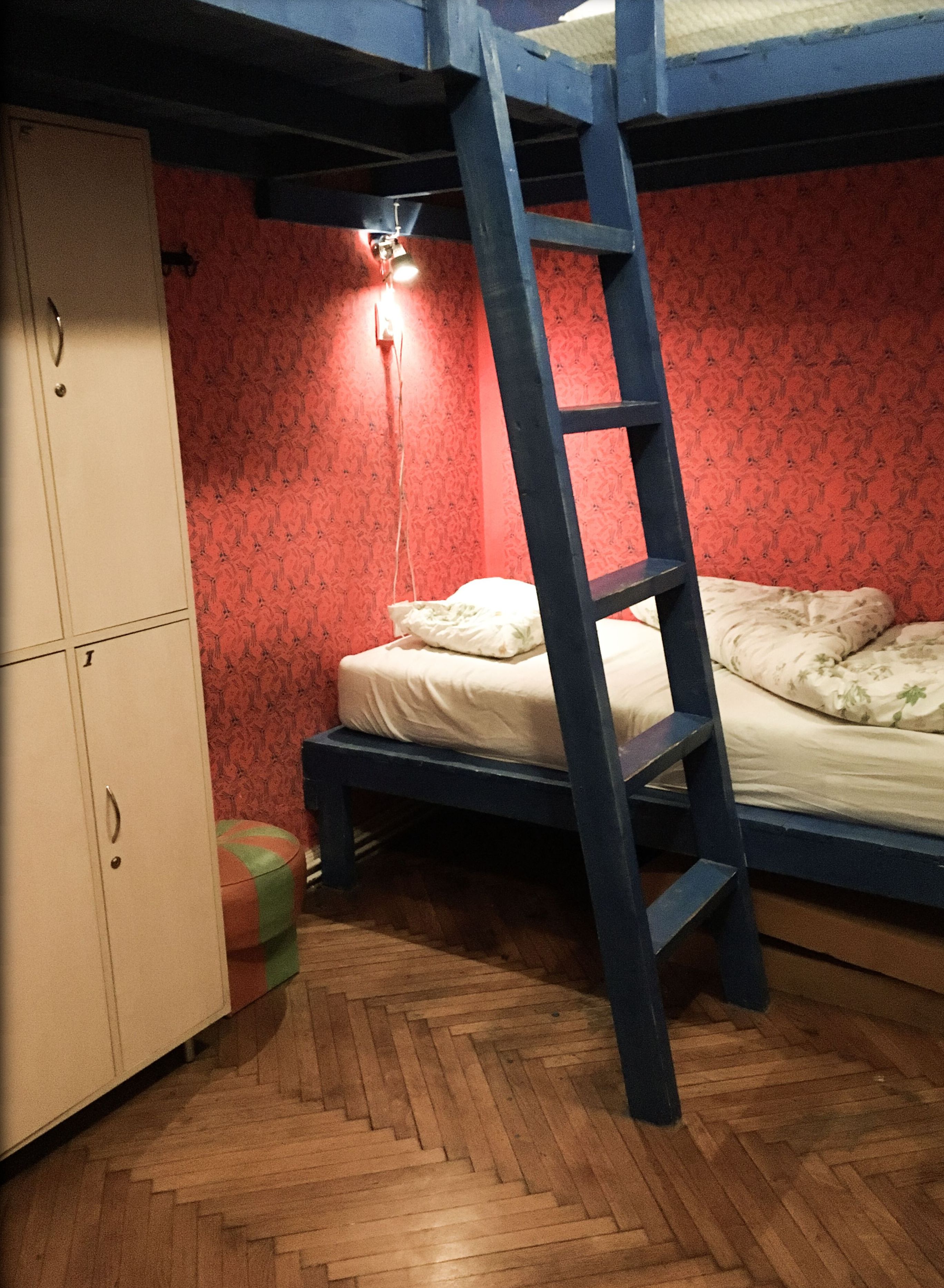 Una cama litera con escalera, un armario y una pared estampada.