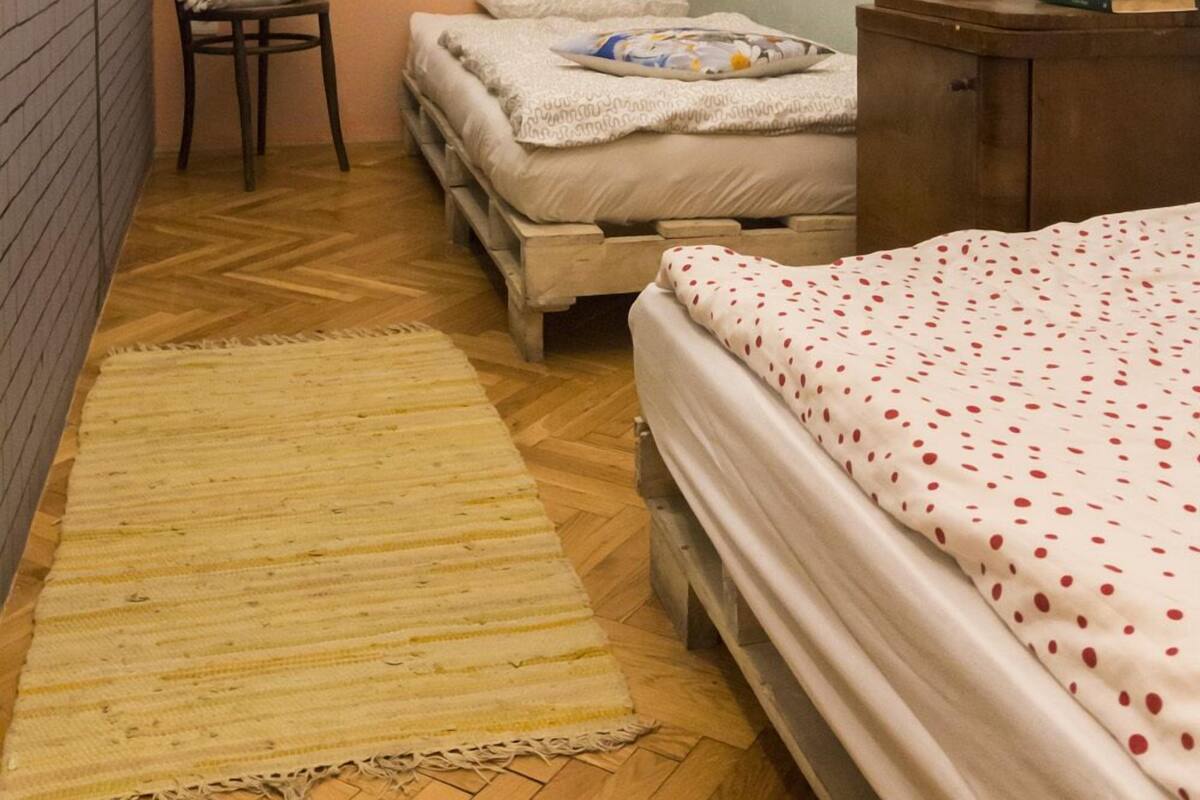 A small, cozy bedroom with a single bed, a chair, a bedside table with a plant, and a window.