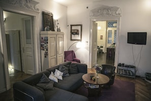 Ein Wohnzimmer mit einer Couch, einem Couchtisch, einem Fernseher und einem Schrank.