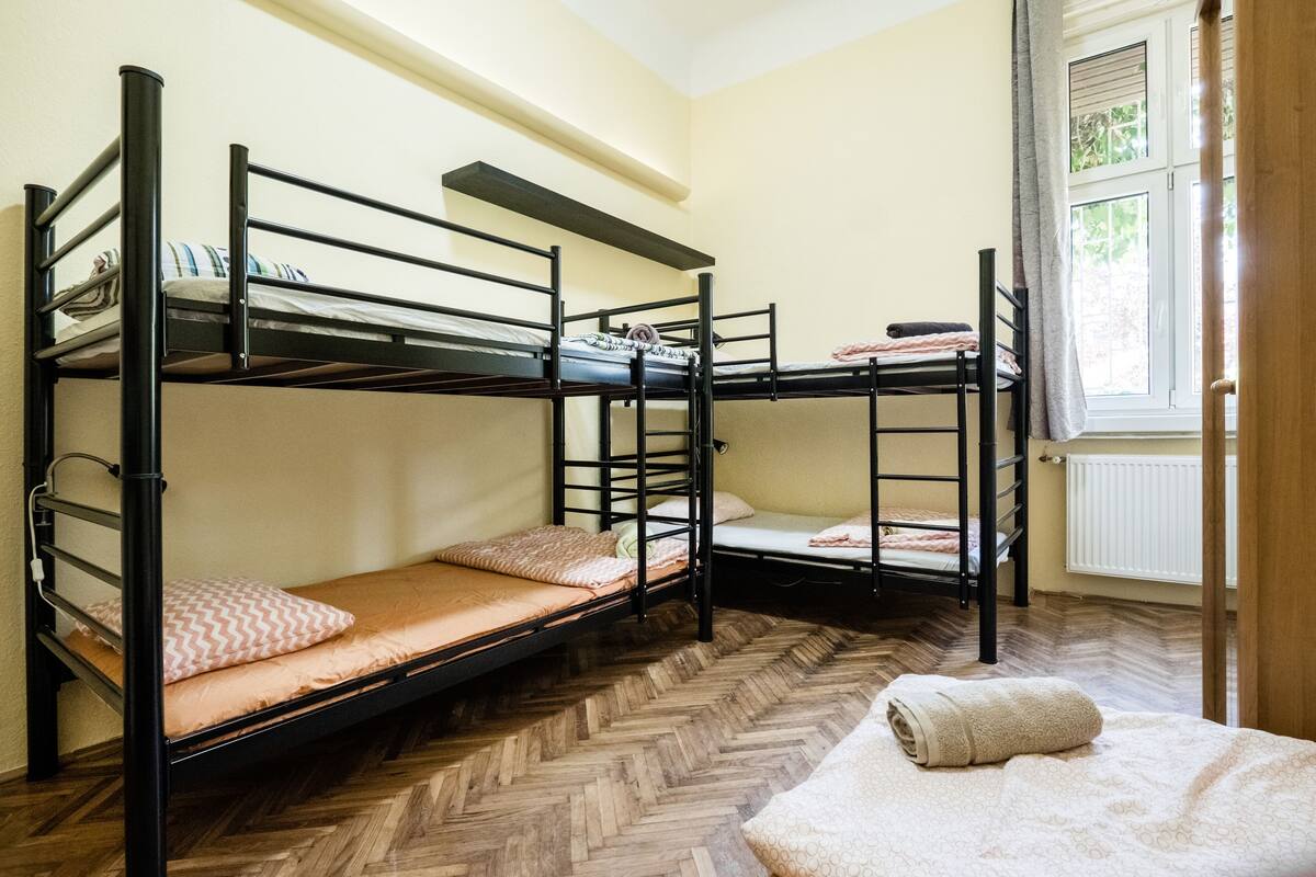 A room with bunk beds, a radiator, and a window with curtains.