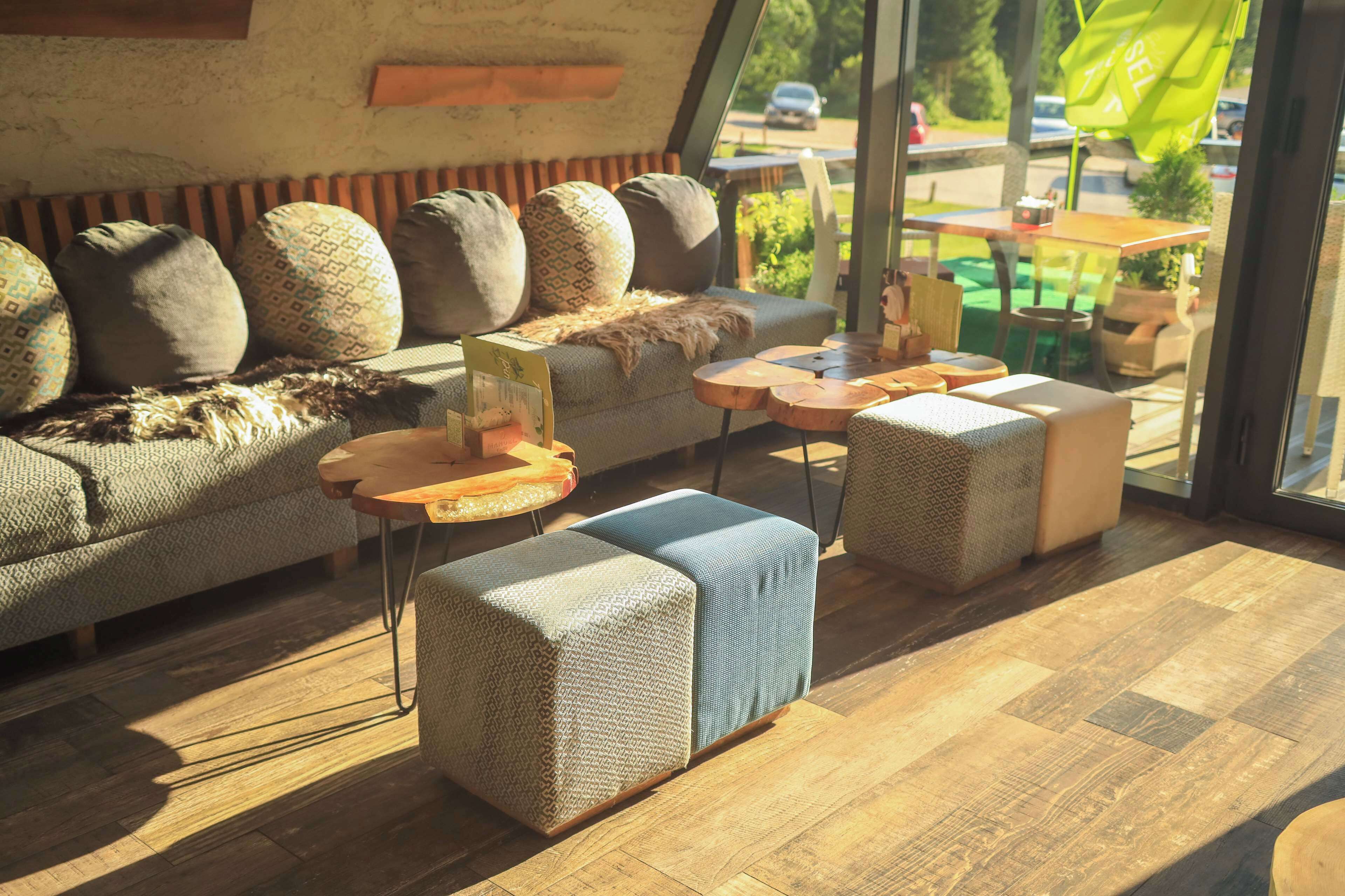 A modern interior with a sofa, ottomans, and round tables.