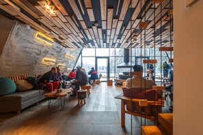 A modern interior with wooden beams, a stone wall, and a large window offering a view of the outdoors. - Pino Nature Hotel, BW Premier Collection (Sarajevo)