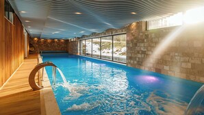 An indoor swimming pool with a wooden deck, stone walls, and a view of the outdoors. - Pino Nature Hotel, BW Premier Collection (Sarajevo)