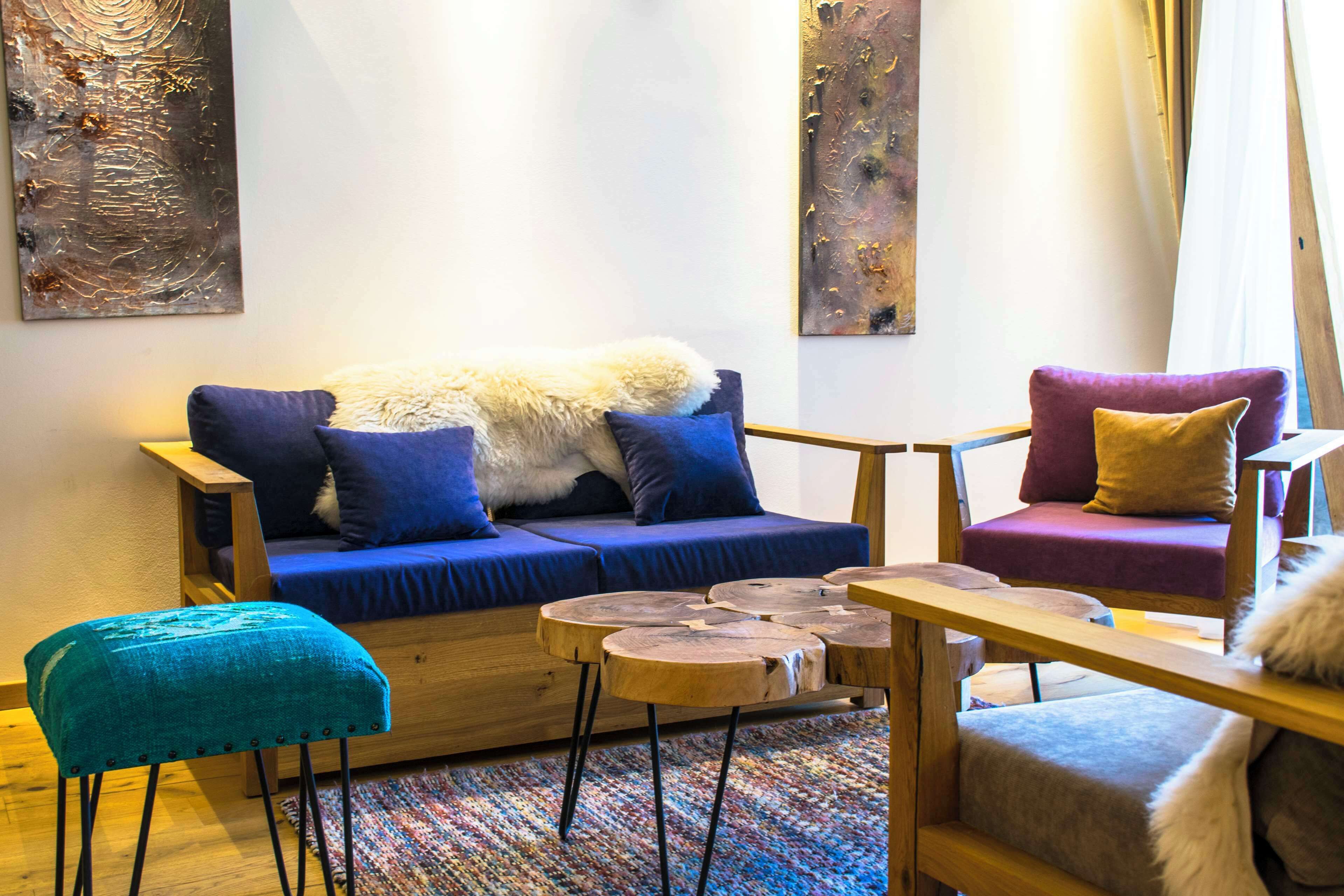 Un salon moderne avec un canapé bleu, un fauteuil violet et une table basse en bois.