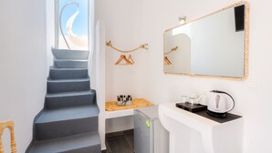 A staircase leading to a room with a view of the sky, a small kitchenette with a refrigerator, and a mirror with a rope frame. - Katris Apartments (Santorini)
