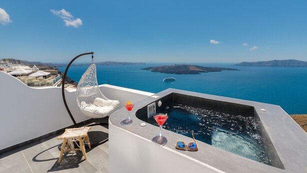 A rooftop terrace with a hot tub, a hanging chair, and a small stool. - Katris Apartments (Santorini)
