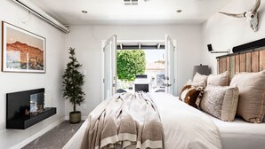 A bedroom with a bed, a bedside table, a wall-mounted TV, a potted plant, and a large window. - Resort Style Escape w/ Modern Conveniences & Location! (Scottsdale)