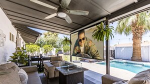 Ein überdachter Außenbereich mit Pool, Deckenventilator und Wandgemälde einer Person in Uniform.
