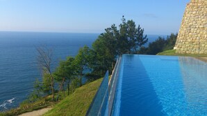 Une piscine offrant une vue dégagée sur l’océan et un bâtiment en pierre.