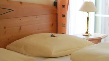 Een hotelkamer met een houten hoofdeinde, een nachtkastje met een lamp en een kussen op het bed.