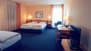 A hotel room with two beds, a desk with a computer and phone, a chair, and a TV. - Hotel Waldeck Garni (Kist)