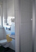 Casa de banho com sanita, lavatório e zona de duche.