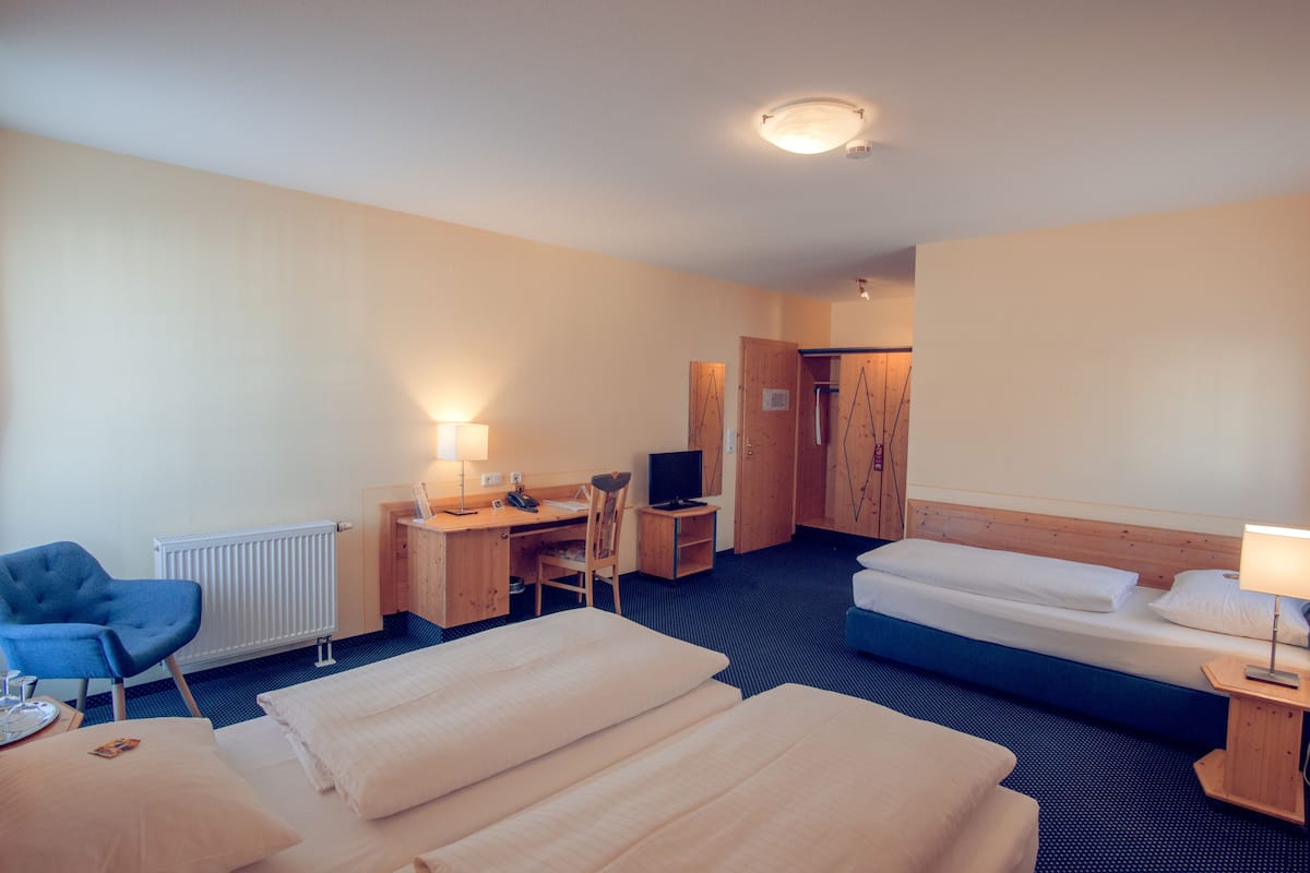 A hotel room with a bed, a desk with a chair, a TV, and a lamp.