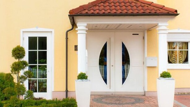 A building with a yellow facade, a red-tiled roof, and a symmetrical entrance with two doors. - Hotel Waldeck Garni (Kist)