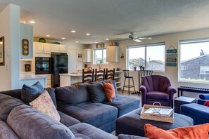 Relax in this cozy living space with a plush sectional sofa and compact kitchen featuring a refrigerator and stove.