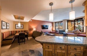 A spacious living area with a large island, seating arrangements, and a television. - Ski In Ski Out At The Largest Resort In The U.S. (Park City)