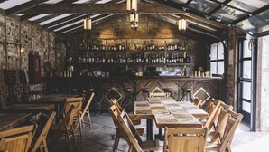 A rustic bar area with wooden tables and chairs, a brick wall, and a variety of bottles on shelves. - Enjoy a spacious private residence loaded with amenities. Minutes to everything! (Nashville)