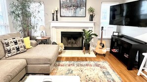 A living room with a sofa, a fireplace, a television, and a guitar. - Enjoy a spacious private residence loaded with amenities. Minutes to everything! (Nashville)